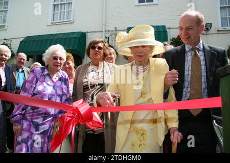 Una signora anziana di giallo limone con un cappello grande apre al nuovo bar/ristorante/sala funzioni sul retro del Crown Hotel Framlingham nel Suffolk Foto Stock