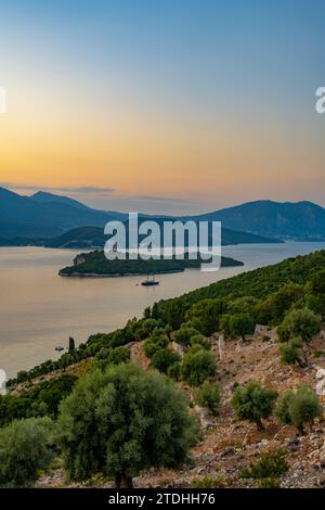 Tramonto dietro l'isola greca di Lefkada e Nisída Thiliá dalla strada sopra Agios Ioannis a Meganisi nel Mar Ionio Foto Stock