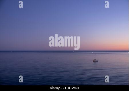 Splendido tramonto sul mare Atlantico con barca a vela in primo piano. Costa dell'Algarve, Portogallo Foto Stock