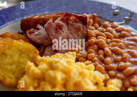 Colazione all'inglese con fagioli al forno, pancetta e uova strapazzate. Messa a fuoco selettiva. Foto Stock