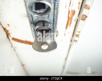 Parte di una vecchia porta. La vernice bianca sta uscendo dal legno. Superficie con vernice per peeling. irregolare. Vecchia maniglia della portiera. Concetto di chiave in una porta. Foto Stock