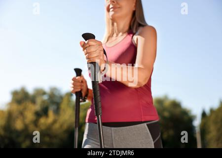 Donna che pratica il nordic walking con i bastoncini all'aperto nelle giornate di sole, primo piano Foto Stock