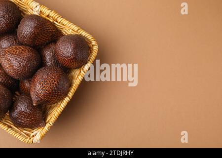 Deliziosa frutta salata nel cestino su sfondo marrone chiaro, vista dall'alto. Spazio per il testo Foto Stock