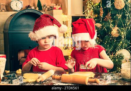 Famiglia di Natale. Giocosi panettieri per le vacanze. Cibo e bevande natalizie. I bambini felici preparano e decorano biscotti natalizi. I bambini preparano i biscotti di natale. Foto Stock