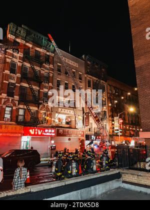 Un camion FDNY applica una scala a un edificio in Bayard Street, a Chinatown di New York, mentre combatte un incendio Foto Stock