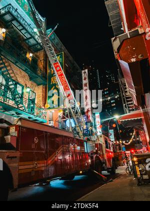 Un camion dei pompieri FDNY con la sua scala si estendeva contro un condominio a Chinatown, New York, mentre assisteva a un incendio Foto Stock