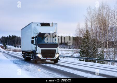 Trasporto di autocarri frigoriferi bianchi lungo l'autostrada in una nuvolosa mattinata invernale. Foto Stock