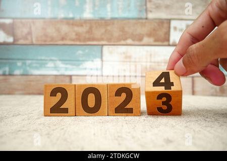 Capovolgimento da 2023 a 2024 su blocchi cubici di legno. A partire dal nuovo anno 2024. Inizio del 2024. Pianificazione del nuovo anno, risultati, obiettivi, business, pla Foto Stock