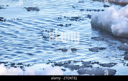 Neve bagnata e frammenti di ghiaccio che si scioglie galleggiano sull'acqua del Mar Baltico, foto di sfondo invernale naturale con messa a fuoco morbida selettiva Foto Stock