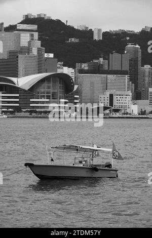 Silenzio sul porto: Una barca vuota che galleggia sulle acque del porto di Victoria, Hong Kong Foto Stock