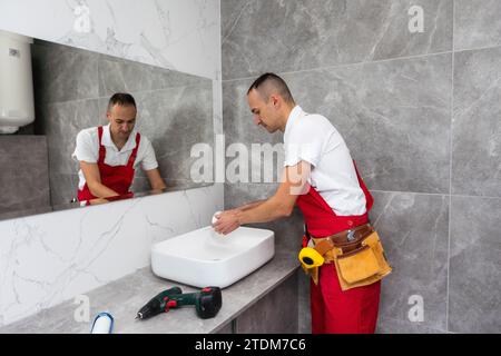 servizio idraulico. Ritratto idraulico vicino all'installazione del sifone del lavabo. Foto Stock