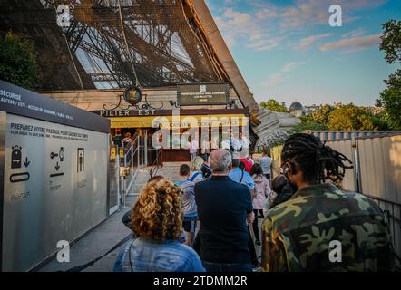 Parigi, Francia, 1 luglio 2022. Persone che fanno la fila per acquistare i biglietti e accedere alla Torre Eiffel. La calda luce del tardo pomeriggio lo illumina completamente. Foto Stock