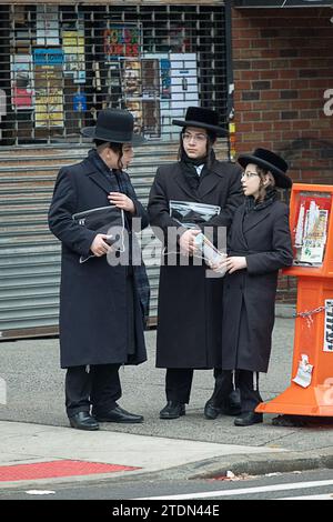 3 ragazzi ebrei ortodossi, probabilmente in viaggio dai servizi del tempio, hanno una conversazione informale all'angolo della strada a Brooklyn, New York. Foto Stock