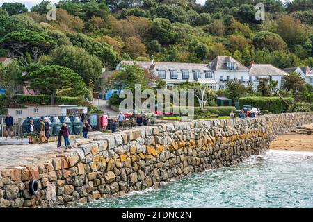 I visitatori aspettano l'arrivo del traghetto Guernsey al porto di Herm, con il White House Hotel sullo sfondo, a Herm, Bailiwick di Guernsey, Isole del Canale Foto Stock