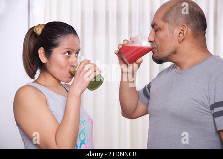 Coppia bevendo frullati verdi e fragole dopo l'attività fisica Foto Stock