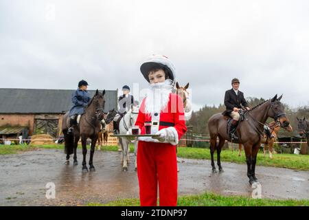 Upper Arley, Kidderminster, Worcestershire, Regno Unito. 19 dicembre 2023. Henley Mills di 10 anni, vestito da Babbo Natale, consegna il tradizionale bicchiere di porto ai membri della caccia ad Albrighton e Woodland, mentre fanno un incontro sul prato e un giro in pista da una fattoria nell'Upper Arley, vicino a Kidderminster, nel Worcestershire. Crediti: Peter Lopeman/Alamy Live News Foto Stock