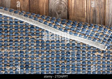 Tappeto in denim geometrico intrecciato a mano su pavimento in legno. Foto Stock