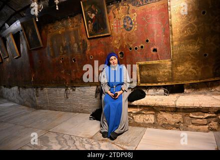 Bethlehem, Cisgiordania. 17 dicembre 2023. Una suora prega nella grotta vuota della Chiesa della Natività, che si ritiene sia il luogo della nascita di Gesù, nella città biblica di Betlemme, Cisgiordania, domenica 17 dicembre 2023. La chiesa, normalmente piena di turisti, è vuota dall'8 ottobre, il giorno dopo che Hamas ha attaccato Israele e la guerra è iniziata nella Striscia di Gaza. I leader cristiani hanno annullato l'erigere l'albero di Natale in Piazza Manager, le gioiose decorazioni di strada e le celebrazioni in solidarietà con i palestinesi a Gaza. Foto di Debbie Hill/ Credit: UPI/Alamy Live News Foto Stock