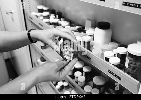 Donna prende barattolo di capsule dal gabinetto della medicina, 22-12-1982, Whizgle News from the Past, su misura per il futuro. Esplora le narrazioni storiche, l'immagine dell'agenzia olandese olandese con una prospettiva moderna, colmando il divario tra gli eventi di ieri e quelli di domani. Un viaggio senza tempo che delinea le storie che plasmano il nostro futuro Foto Stock