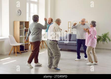 Gruppo di anziani uomini e donne che si divertono e ballano in casa di riposo. Foto Stock