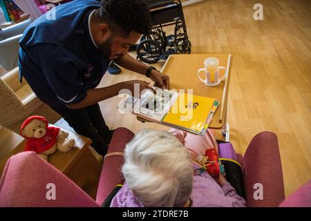 Infermiera Evans Sorbeng (dal Ghana) con la residente Angela Morgan (76) nella sala diurna della St Cecilias Nursing Home Scarborough St Cecilias Nursing Home Scarborough. Foto Stock