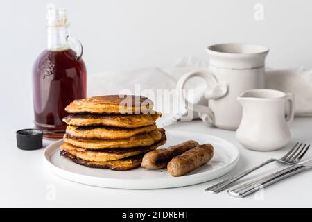 Una pila di pancake di patate dolci serviti con sciroppo d'acero e salsicce. Foto Stock