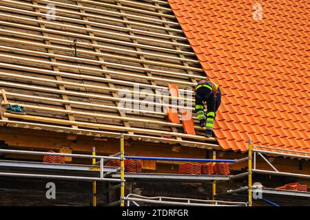 Tegole in indumenti da lavoro protettivi installazione di nuove tegole in argilla, nuova copertura in strato di piastrelle in argilla Foto Stock