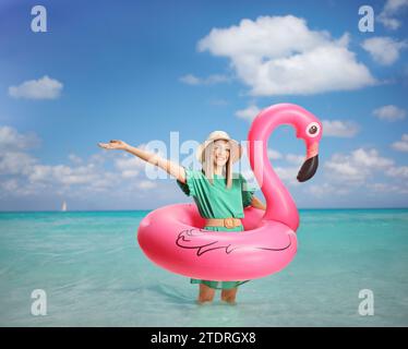 Giovane donna felice con un anello di gomma flamingo in mare Foto Stock