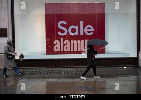 Gli acquirenti di Natale approfittano delle vendite all'inizio del periodo festivo su Oxford Circus, nel West End di Londra, in una giornata invernale umida, Inghilterra, Regno Unito Foto Stock