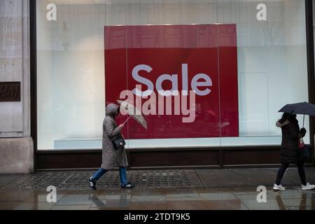 Gli acquirenti di Natale approfittano delle vendite all'inizio del periodo festivo su Oxford Circus, nel West End di Londra, in una giornata invernale umida, Inghilterra, Regno Unito Foto Stock