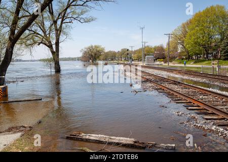 I binari ferroviari stanno per essere superati da un fiume allagato. Foto Stock