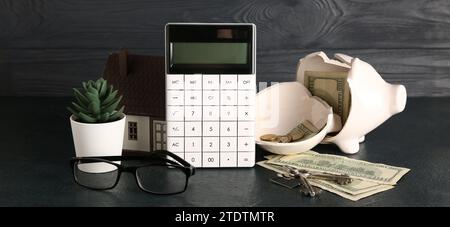 Calcolatrice, salvadanaio rotto, soldi, occhiali da vista e modello di casa su sfondo scuro Foto Stock