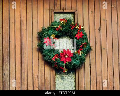 Corona di Natale, sulla porta anteriore in legno marrone. Decorazioni. Buone vacanze a tutti. Foto Stock