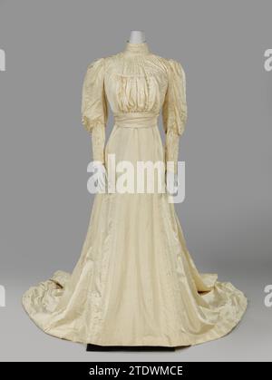 Abito da sposa con gamba di maniche di montone, M.A. van Asch, 1908 abito da sposa in seta ottomana color crema, composto da un corpo (A) e una gonna con rete a strascico (B). Modello: Corpo altamente collegato con colletto verticale con nervature. Sotto una spalla semicircolare con sollevamento verticale. Il giorno del matrimonio era appeso un lato largo della striscia (ora mancante). Sotto la fascia larga. Maniche larghe, che si avvicinano molto al gomito e finiscono nella mano in un punto. Chiusura tramite ganci e occhielli nella giunzione laterale. Chiusura di abito al centro anche con ganci e occhi. La cintura è ruvida Foto Stock