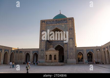 28 GIUGNO 2023, BUKHARA, UZBEKISTAN: Veduta della madrasa araba Mir i attraverso la vecchia porta intagliata in legno, Bukhara, Uzbekistan Foto Stock