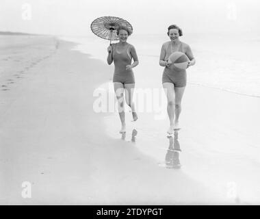 La modella Eva Waldschmidt (con ombrellone) e Nell Langlais camminano lungo la linea della marea a Zandvoort ca. 1932 Foto Stock