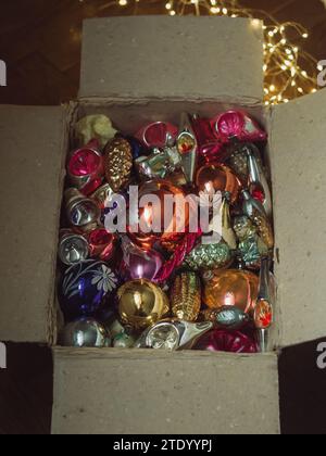 Immagine verticale direttamente dall'alto di una vecchia scatola aperta con decorazioni vintage sull'albero di Natale e luci elettriche moderne. Magia del tempo dell'avvento Foto Stock