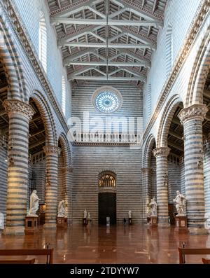 Orvieto, Italia - 18 novembre 2023: Vista interna della navata centrale del Duomo di Orvieto con panche e molte statue Foto Stock