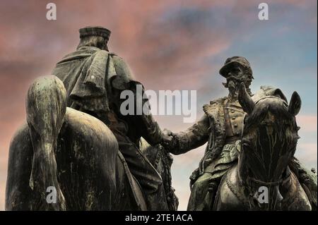 Monumentale statua bronzea dell'incontro a Teano, realizzata nel 1906 dallo scultore Oreste Calzolari (1852-1920) e oggi in piazza Mino da Fiesole, la piazza principale di Fiesole, città sopra Firenze, Toscana, Italia. Raffigura l'incontro del 26 ottobre 1860 che ha sigillato l'unità d'Italia. Il generale repubblicano e nazionalista, Giuseppe Garibaldi (1807-1882) (a sinistra), e il re Vittorio Emanuele II (1820-1878), entrambi a cavallo, stringevano la mano su un ponte a Teano in Campania. Foto Stock