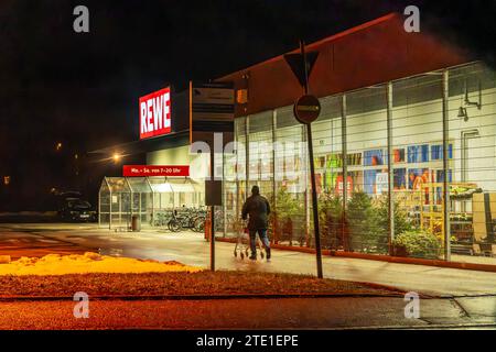 Einsamer Kunde vor REWE Supermarkt abends nach 19 Uhr, Lebensmittel kaufen für Weihnachten, Neubiberg bei München, Dezember 2023 Deutschland, Neubiberg bei München, dicembre 2023, letzte Einkäufe im REWE Supermarkt abends nach 19 Uhr, Kunde schiebt Einkaufswagen zum Eingang des Supermarkts, Öffnungszeiten 7 - 20 Uhr, Winterwetter, Geschäfte, Adventszeit, Weihnachtszeit, Wirtschaft, Winter, Bayern, *** cliente solitario di fronte al supermercato REWE la sera dopo le 19.00, acquisto generi alimentari per Natale, Neubiberg vicino a Monaco, dicembre 2023 Germania, Neubiberg vicino a Monaco, dicembre 2023, ultimo sh Foto Stock