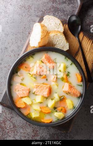 Zuppa cremosa di pesce rosso fatta in casa con verdure e aneto su un piatto servito con pane da vicino sul tavolo. Vista dall'alto verticale Foto Stock