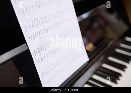 Foto di STILL Life. Vista ritagliata del vecchio pianoforte classico in legno d'epoca e note musicali su foglio di carta bianca. Strumento musicale Chord Foto Stock