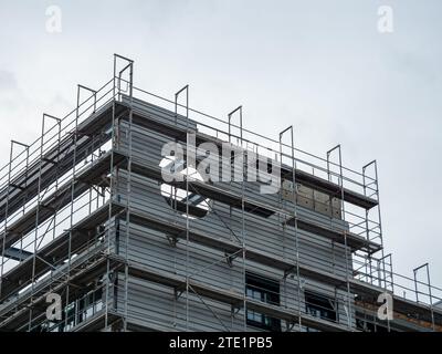 Impalcature in un cantiere di un edificio residenziale. Il muro esterno e la facciata sono in costruzione. L'isolamento fa parte dell'installazione. Foto Stock