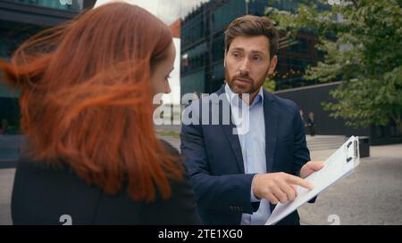 Colleghi d'affari, uomo e donna, che discutono di un contratto d'affari scadente nei partner della città che hanno una controversia in merito a termini inaccettabili per i documenti Foto Stock