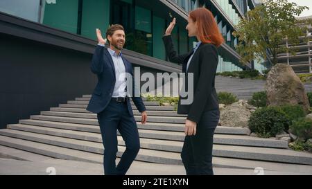 Partner aziendali uomini d'affari e donne d'affari che si recano in una riunione cittadina celebrano cinque gesti entusiasti colleghi Foto Stock