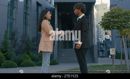 Uomo d'affari indiano donna d'affari araba ragazza uomo d'affari partner colleghi colleghi che si incontrano in città salutando formale stringere le mani maschio Foto Stock