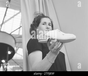 Fiera internazionale delle calzature a Jaarbeurs a Utrecht, donna che tiene una scarpa ca. 13 aprile 1964 Foto Stock