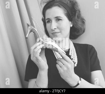 Fiera internazionale delle calzature a Jaarbeurs a Utrecht, donna che tiene una scarpa ca. 13 aprile 1964 Foto Stock