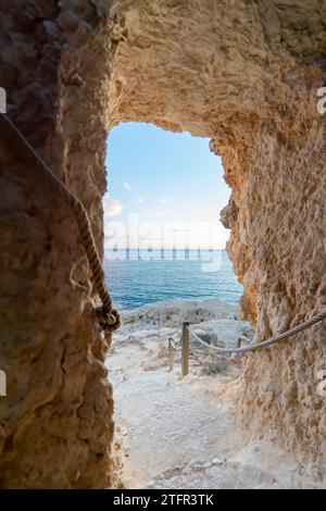 Uno scorcio di serenità: Vista verticale a basso angolo dall'interno di una grotta in Portogallo, affacciata sul tranquillo oceano Atlantico Foto Stock