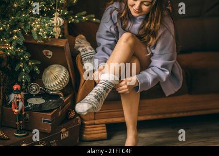 Primo piano dei piedi femminili in calze di Natale bianche con ornamento. Festa di Capodanno, Natale. Dischi in vinile Foto Stock